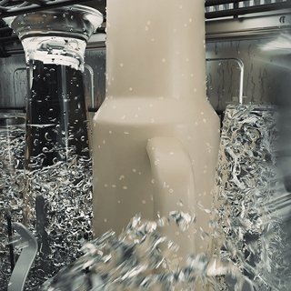 A large tumbler cup being sprayed for an Ultra Wash.