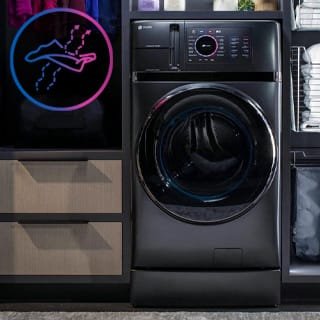A front facing shot of the Washer/Dryer. An icon of a drying sheet of cloth is superimposed in the corner A front facing shot of the Washer/Dryer. An icon of a drying sheet of cloth is superimposed in the corner